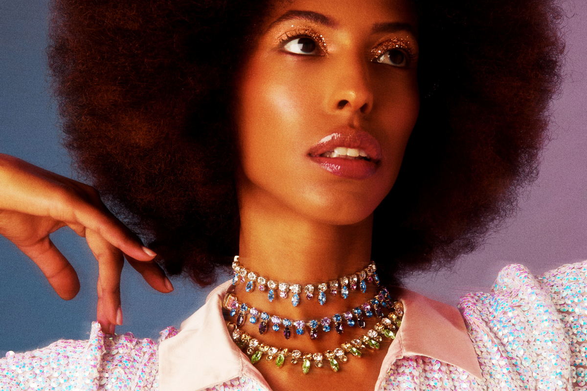 A woman with an afro wears 3 crystal chokers